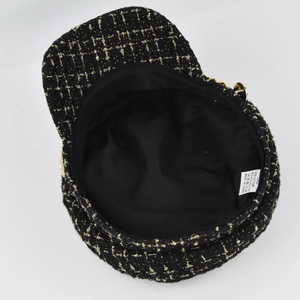 Detail view of tweed newsboy cap with gold thread weave, inner lining and care label