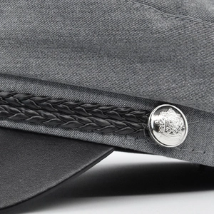 Vintage gray newsboy cap with black leather visor and embossed heraldic metal button detail