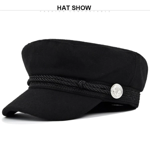 Detail of black baker boy hat featuring braided rope and silver anchor metal buttons