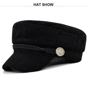 Detailed close-up of black sherpa newsboy hat with gold crown button and rope trim