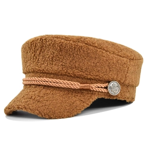 Detailed macro view of brown faux shearling baker boy cap with crest metal button
