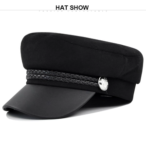 Detail of black newsboy hat featuring textured wool top and silver metallic button
