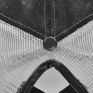 Macro detail of washed black cotton fabric and mesh ventilation on baseball cap top