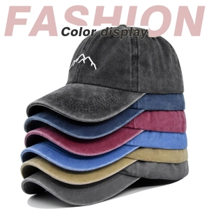 Vertical stack of washed cotton baseball caps showing various colors and mountain embroidery