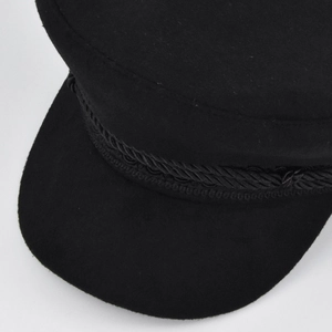 Detail of the black wool baker boy hat featuring a thick braided rope and metal buttons