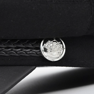 Black wool newsboy cap featuring detailed silver crest button and braided leather strap