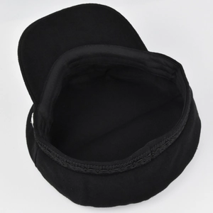 Detail view of the black wool baker boy hat featuring a flat top and braided band