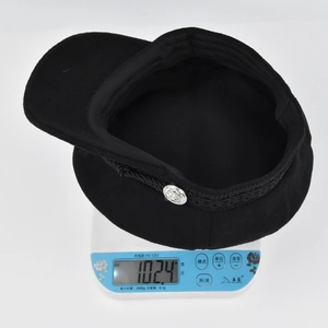Close-up of a black wool flat top captain hat with braided rope and metal button detail