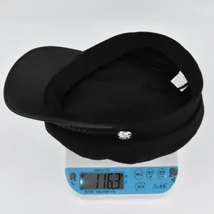 Weight measurement of black newsboy hat showing 116.3g on scale with cotton blend material
