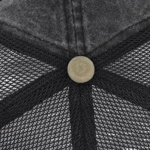 Détail macro du bouton en velours côtelé, tissu coton et maille filet de la casquette