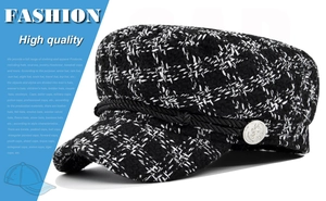 Detail of black and white plaid newsboy cap with silver anchor button and braided cord