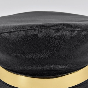 Close-up of black lychee grain leather flat top hat with a glossy gold metal band detail