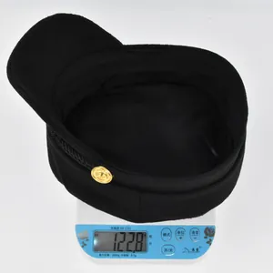 Mesure du poids d'une casquette gavroche noire avec bouton doré, 122.8g