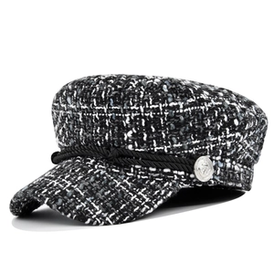 Detailed close-up of black and white tweed newsboy cap with silver anchor button