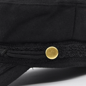 Détail d'un béret marin noir en laine avec cordon tressé et bouton doré métallique