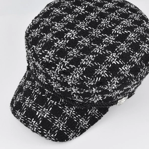 Detail view of black and white tweed newsboy cap with braided rope and silver button