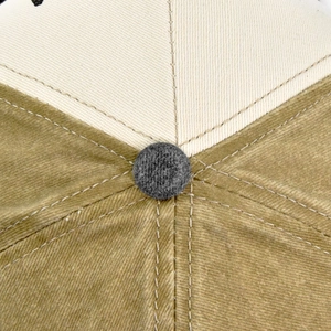 Detail of baseball cap top button showing contrast stitching and textured khaki fabric