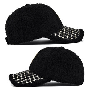 Dettaglio del cappello da baseball in lana di agnello nera con visiera in tweed e oro