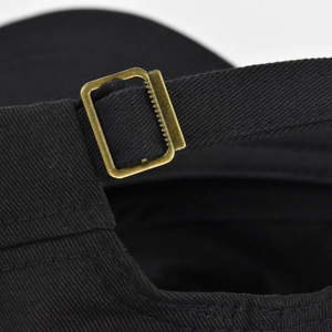 Detail of adjustable brass buckle and cotton fabric texture on back of black baseball cap