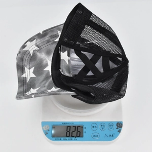 Detail showing the gray star pattern baseball cap on a digital scale weighing 82.6 grams