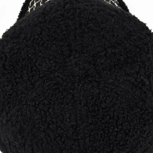 Dettaglio ravvicinato della trama in pile sherpa nero di un cappellino con fibre spesse