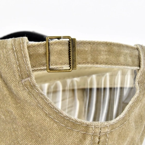 Macro detail of the bronze metal adjustment buckle on the washed cotton baseball cap
