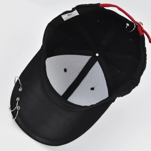 Detail view of black cotton baseball cap with silver metal rings and red webbing strap