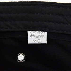 Detail of internal wash care label and breathable metal eyelet on a black sport cap