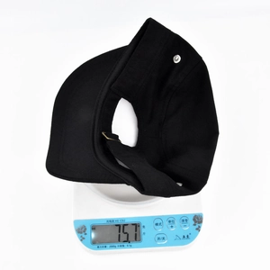 Detailed view of a lightweight black sun visor for ponytails weighing 75.7g on a scale