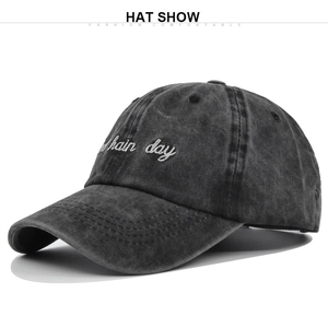 Detailed view of white main day embroidery on a dark grey washed vintage cotton baseball cap