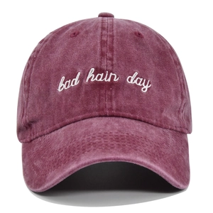 Close-up of white Bad Hair Day embroidery on washed burgundy cotton baseball cap