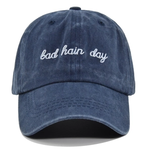 Macro view showing 3D white Bad Hair Day embroidery on washed blue cotton baseball cap