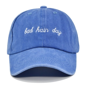 Close-up of white Bad Hair Day embroidery on a washed blue vintage cotton baseball cap