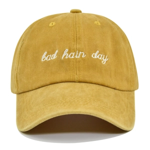 Close-up of white 3D embroidery 'bad hair day' on washed yellow baseball cap