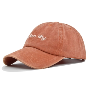 Close-up of white 3D embroidery detail on washed cotton baseball cap in brick red
