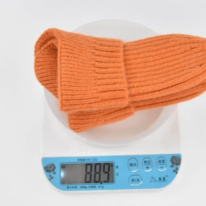 Detail shot showing 88.9g weight of orange knit ponytail beanie on a digital scale