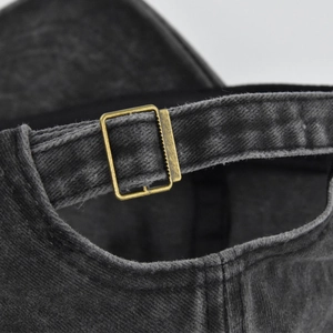 Detail of vintage washed denim baseball cap with antique bronze metal buckle closure