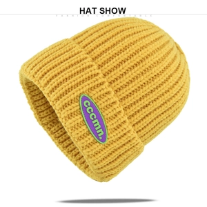 Close-up of yellow knit beanie featuring thick rib texture and oval cccmn logo patch