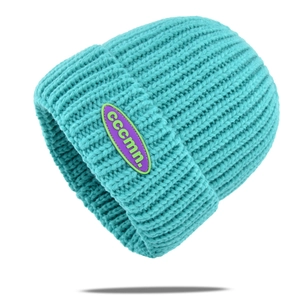 Detail of turquoise ribbed knit beanie with purple brand patch showing texture
