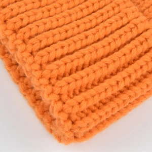 Close-up of orange knitted beanie showing thick ribbed texture and soft woolen fibers