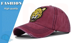 Close-up of leopard head embroidery on burgundy washed cotton baseball cap with worn brim