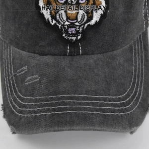 Close-up of vintage grey washed baseball cap featuring 3D tiger head embroidery and distressed holes