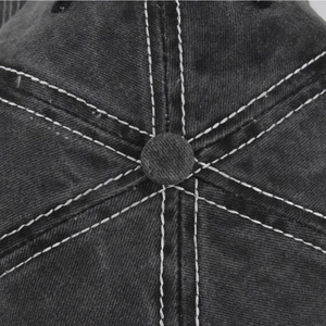 Detail of contrast stitching and top button on a washed grey cotton baseball cap