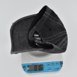 Detailed view of the embroidered baseball cap weight on a digital scale showing 81.6g