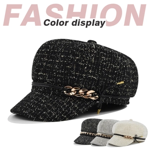 Détail de la casquette gavroche en tweed avec chaîne dorée et texture de tissu riche
