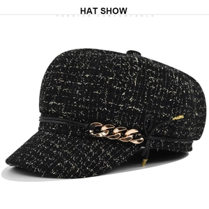 Détail de la casquette gavroche en tweed noir avec chaîne dorée et ruban décoratif