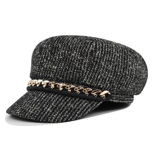 Détail de la casquette gavroche en tweed noir et blanc avec chaîne dorée et haut plat