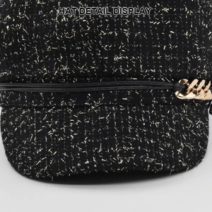 Détail de la casquette gavroche en tweed avec fil doré et décoration de chaîne dorée