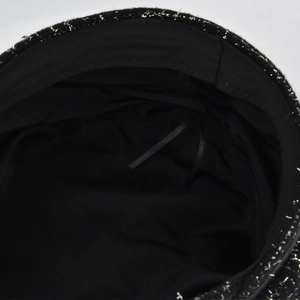 Détail d'un béret en tweed noir et doré avec cordon de serrage intérieur ajustable