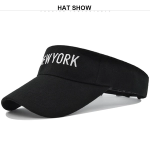Detail of white NEW YORK embroidery on a black cotton sun visor hat with curved brim